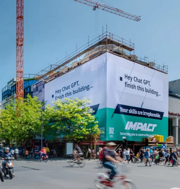 I guess we still need skilled humans after all. An ad draped over an unfinished building in Antwerp, Belgium.